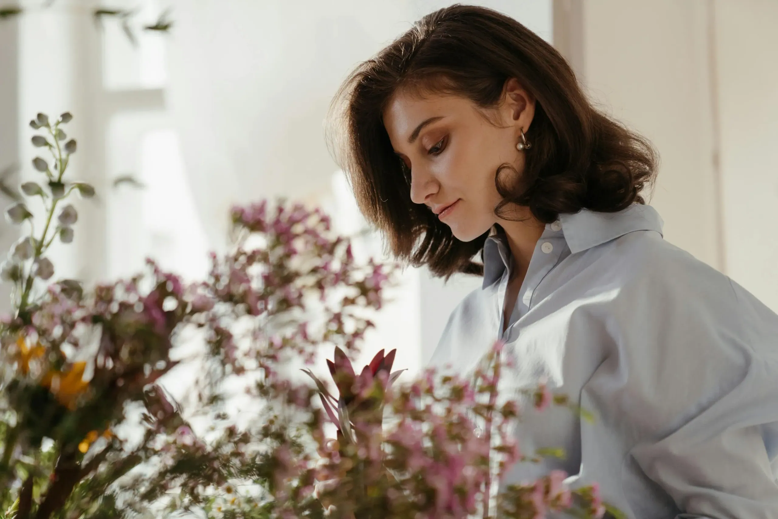A woman arranging flowers by a window